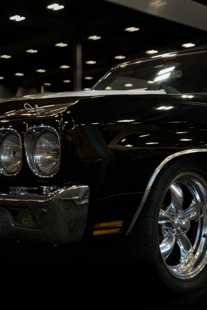 Ceramic Coating Close-up of a black vintage car with chrome rims showcased indoors, highlighting details and classic design.