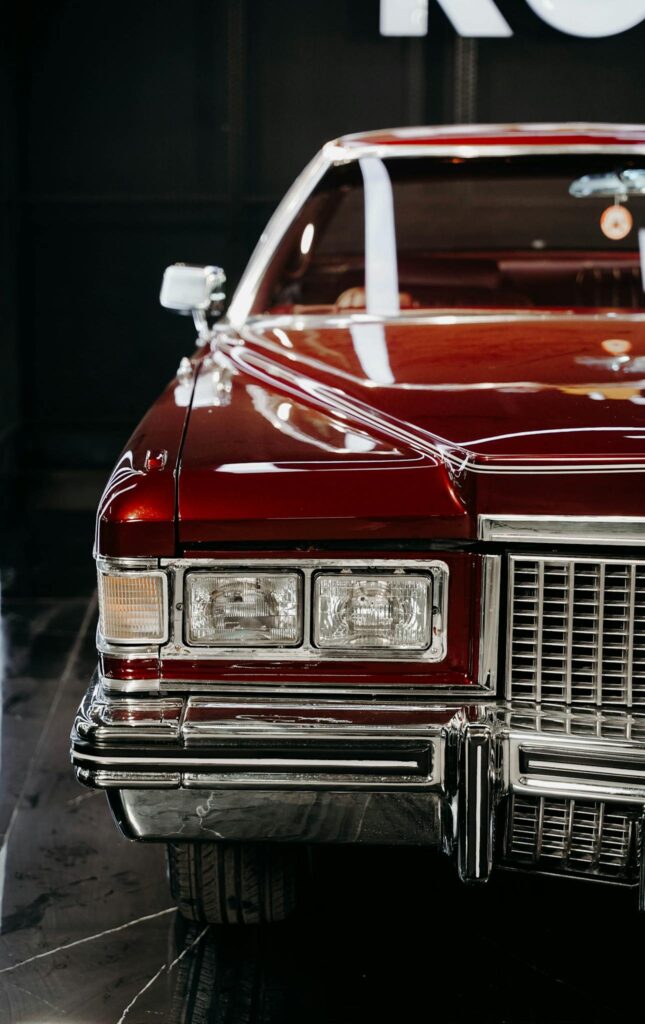 Front view of a vintage Cadillac with shiny chrome and classic headlight design, showcasing retro elegance.